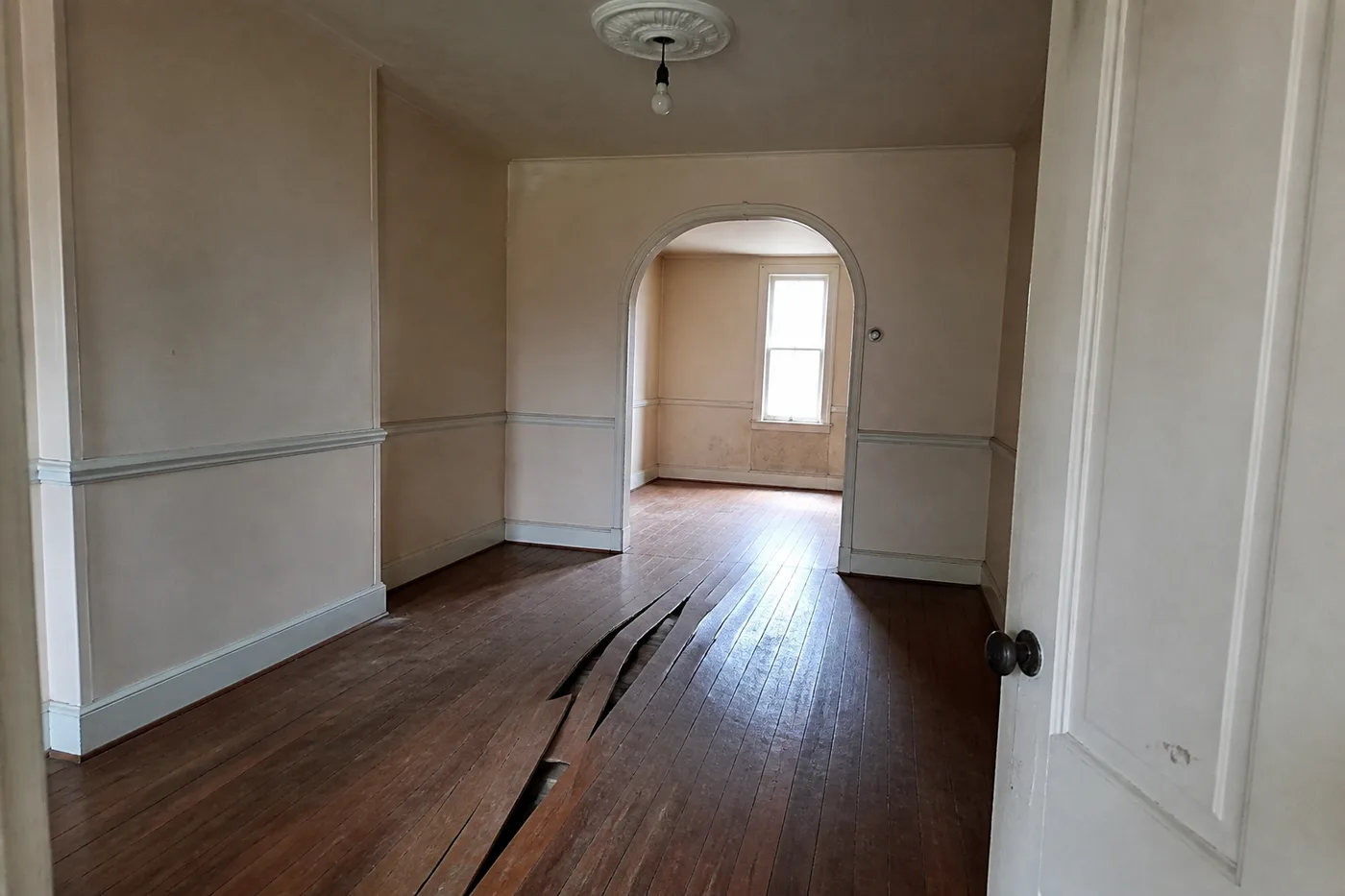 Hardwood floorboards buckled into a raised ridge across a dining room floor