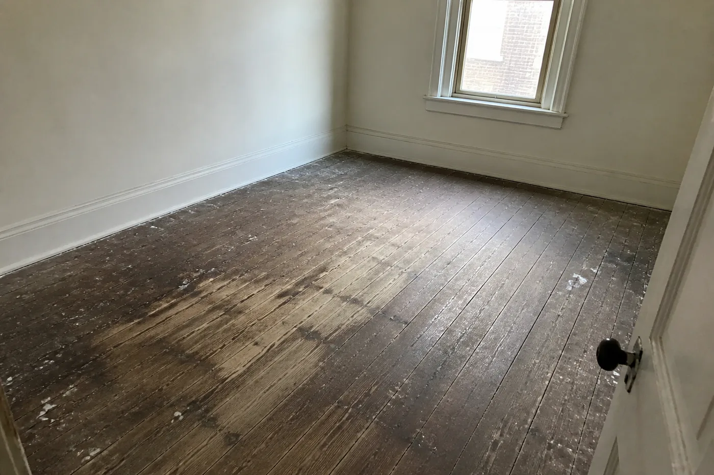 Grimy, paint-spattered original wide-plank heart pine floor worn grey in places