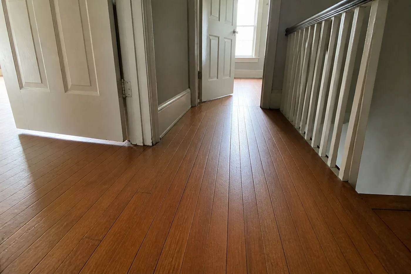 The same landing with replaced boards blended in and the floor refinished in an even warm stain